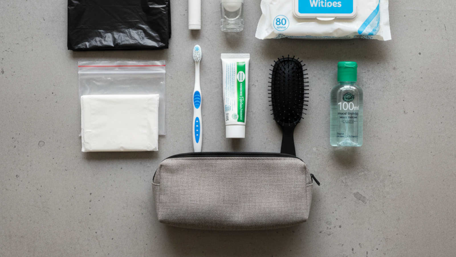 A neatly arranged collection of travel-sized toiletries, wet wipes, and hand sanitiser for a UK emergency grab bag.