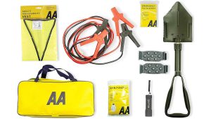 AA winter car kit contents laid flat — yellow AA holdall, jump leads, adults high-visibility vest, folding army shovel, snow grips, rain poncho, emergency foil blanket, and LED torch — UK Prepper Hub