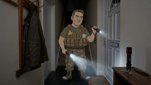 Cartoon Keith in a dark hallway during a power cut, holding Lepro torches, with another Lepro torch by the front door